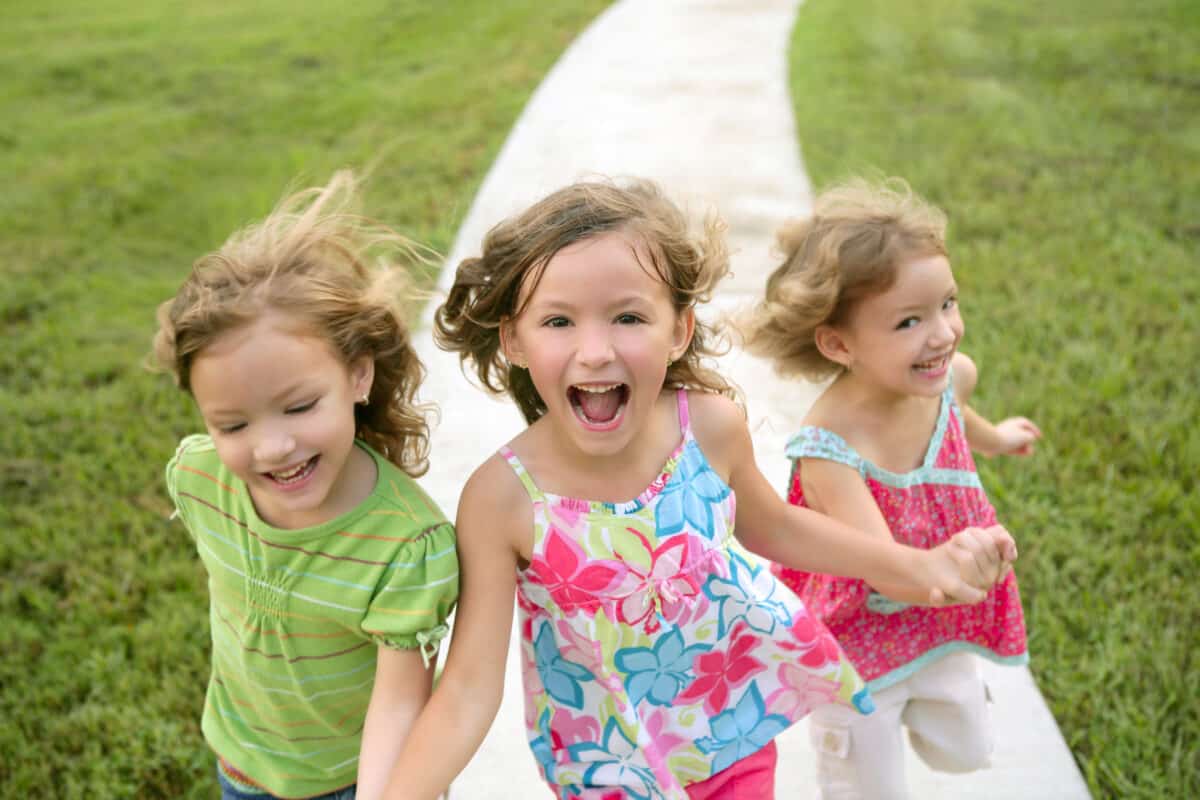 Three sister girls playing running on the park